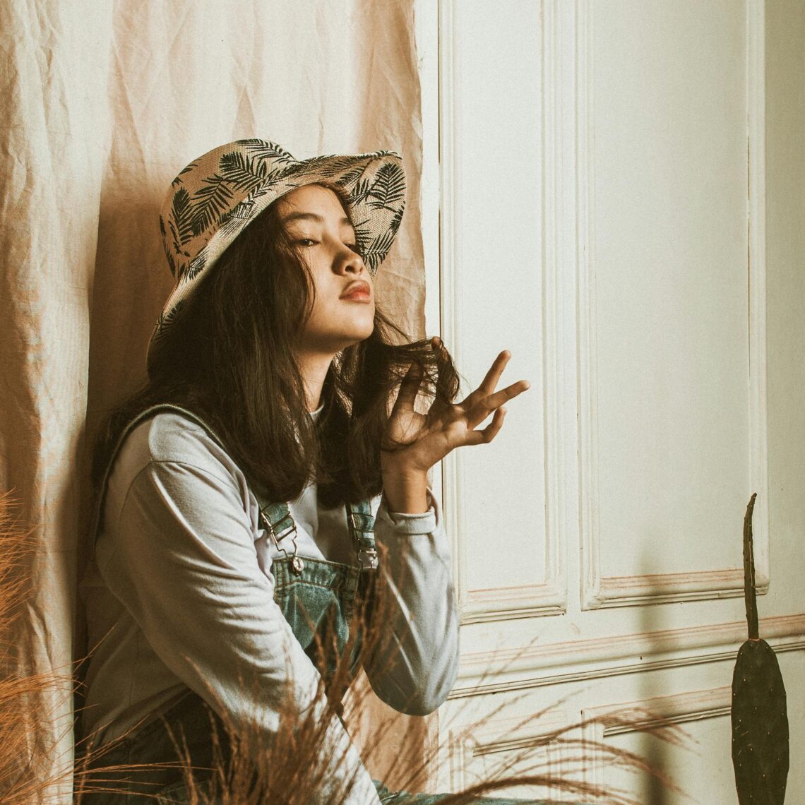 A trendy young woman in casual fashion relaxes inside, embodying serene lifestyle.